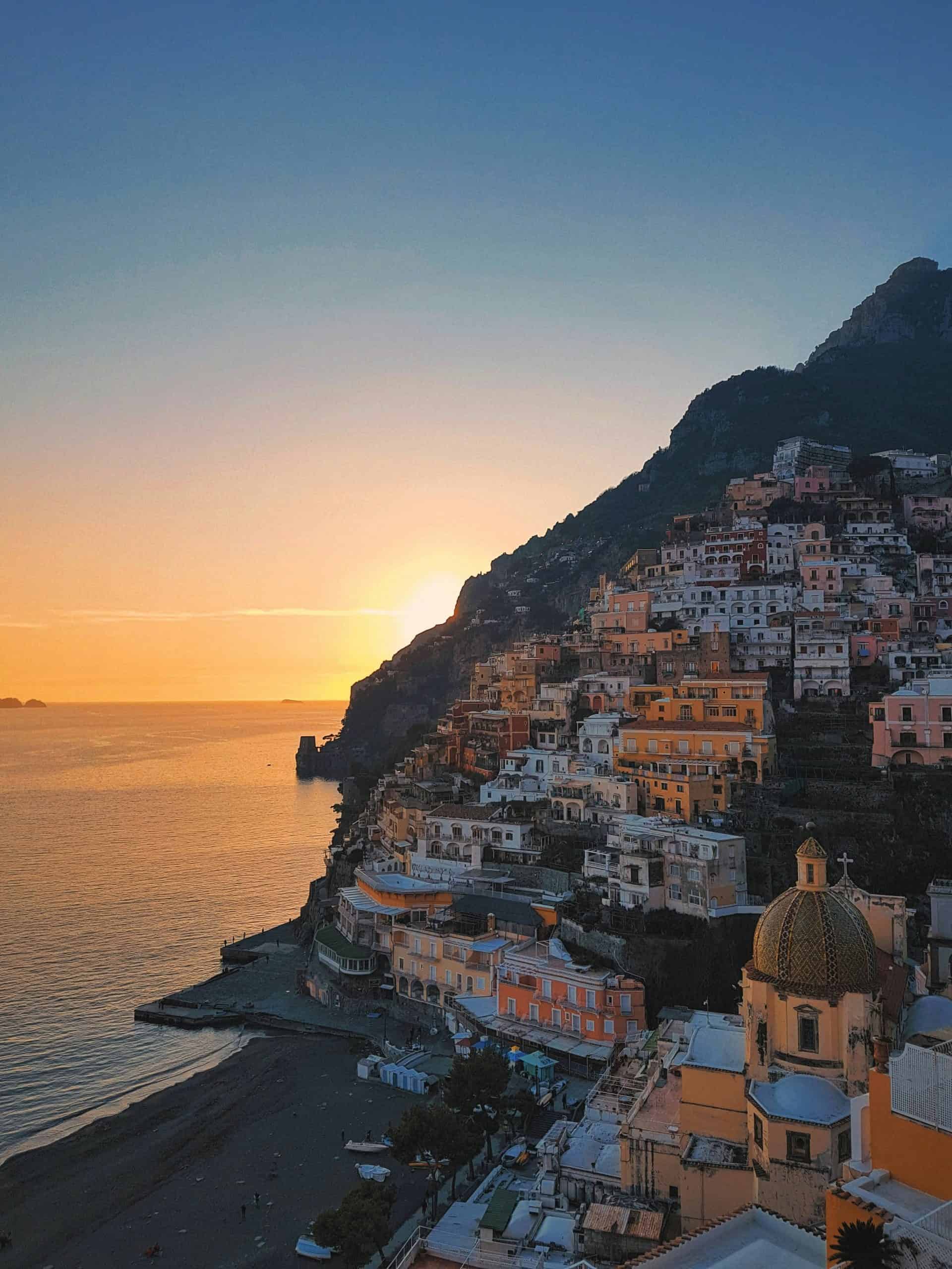 Positano cliffside colourful buildings and sun setting in the background