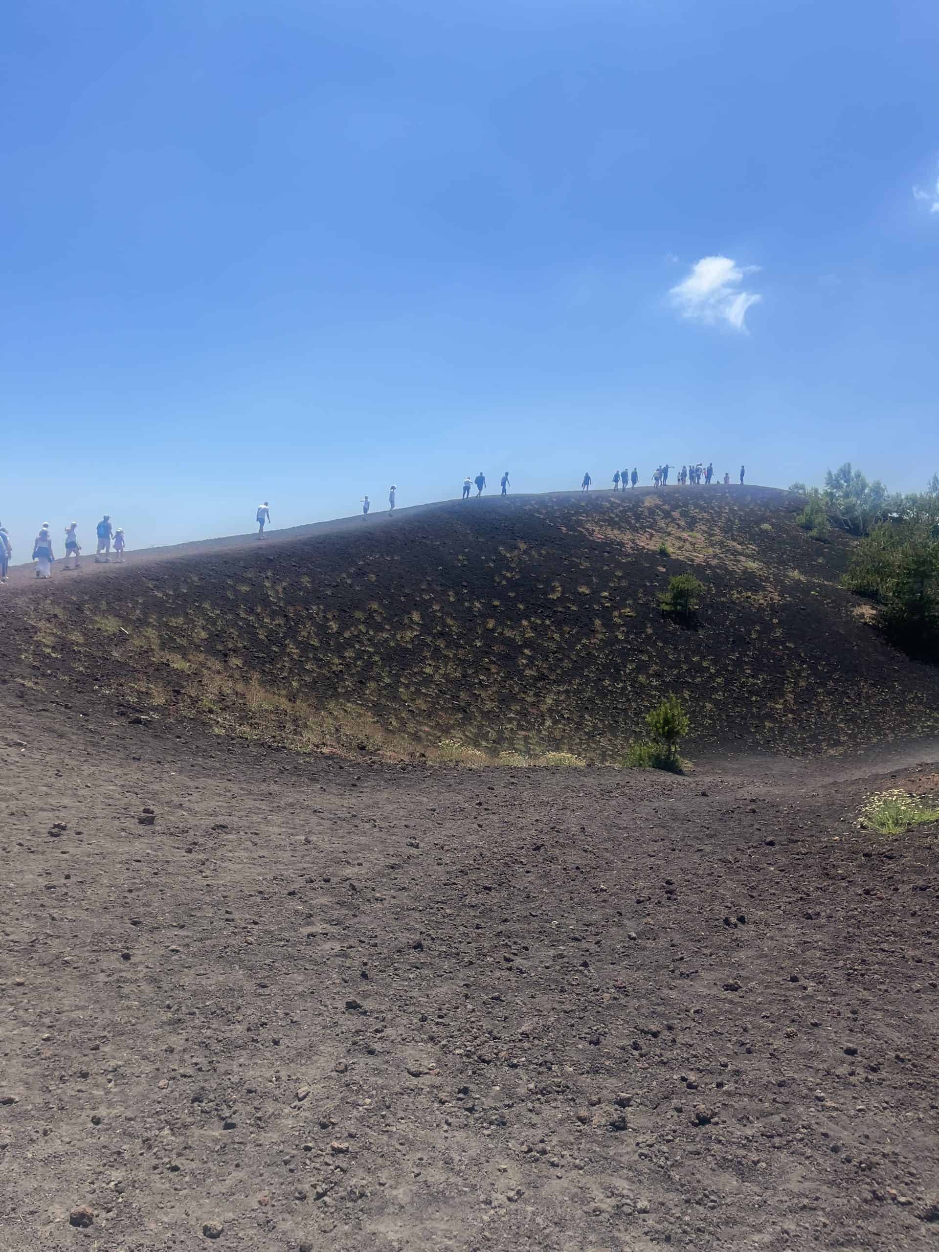 a row of people walking high up on a volcano crater