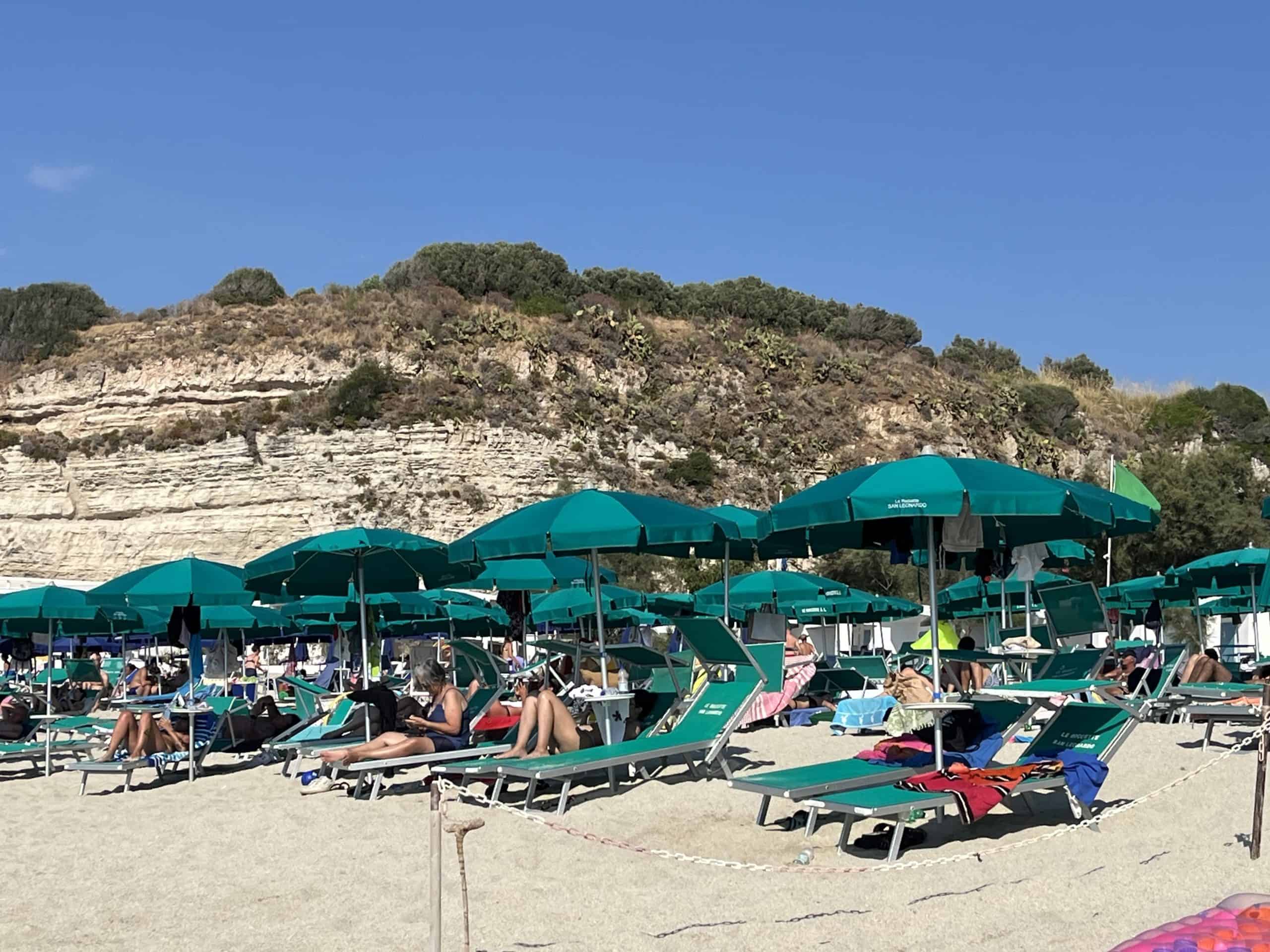 Rows of people sitting on chairs and under umbrellas on the beach