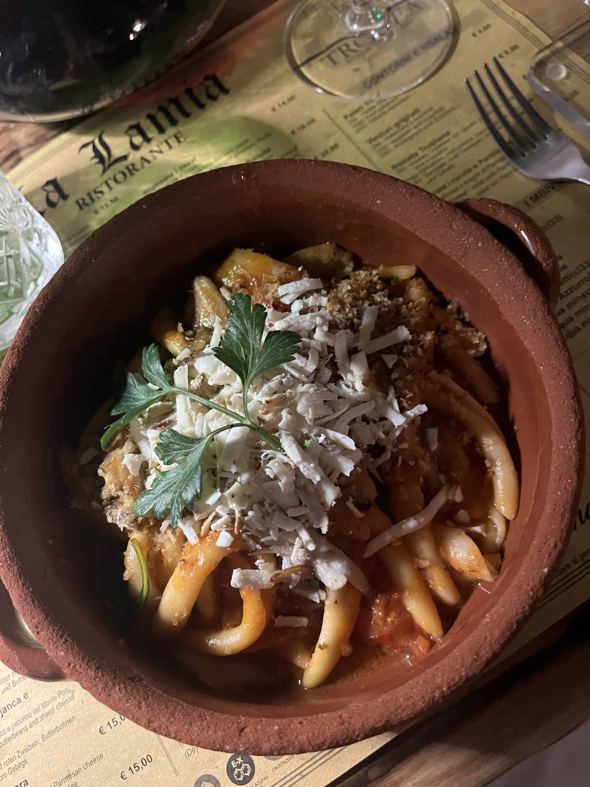 Fileja pasta in a nduja tomato sauce with cheese sprinkled on top in a clay bowl