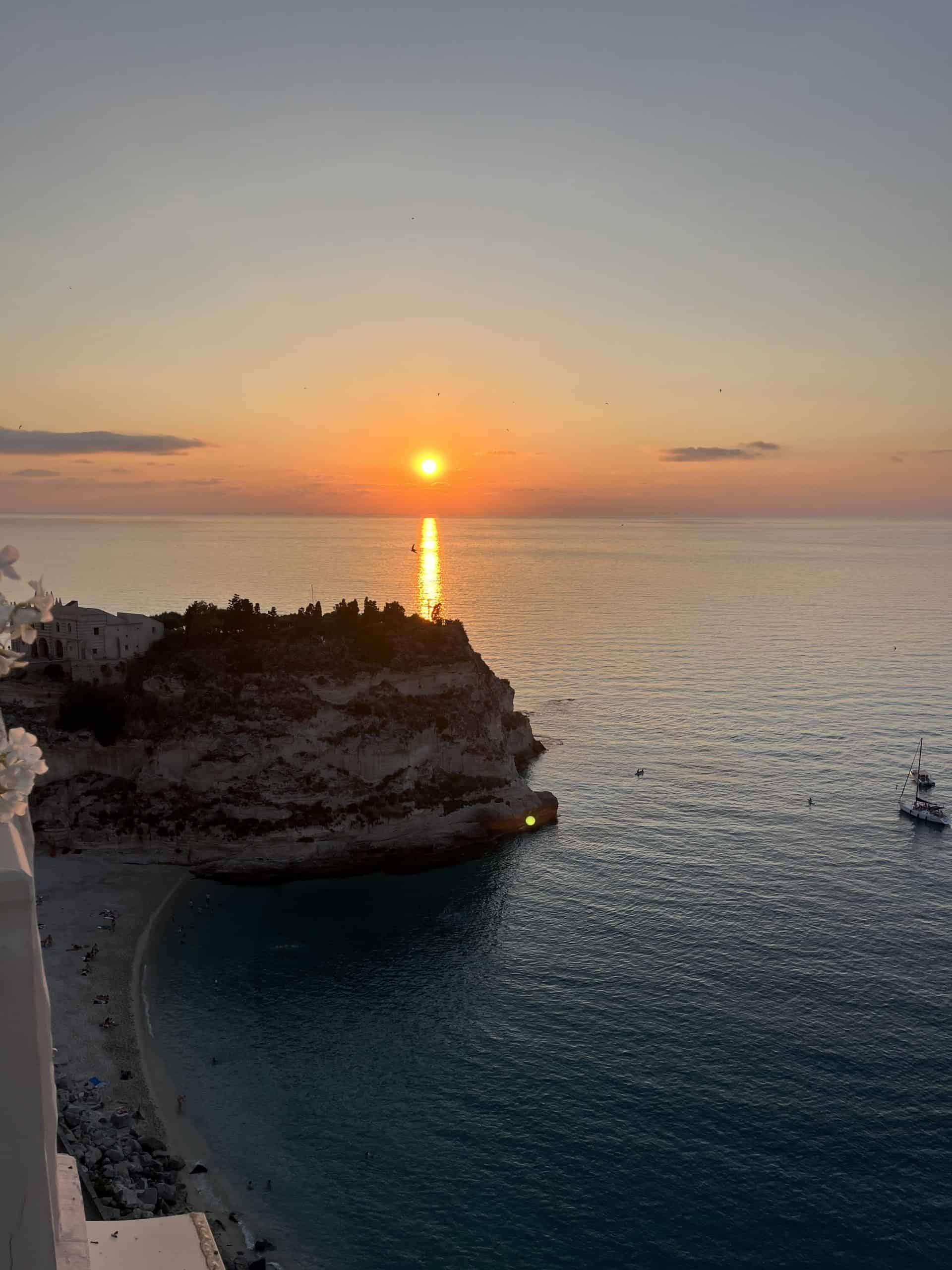Orange coloured sun setting behind an island