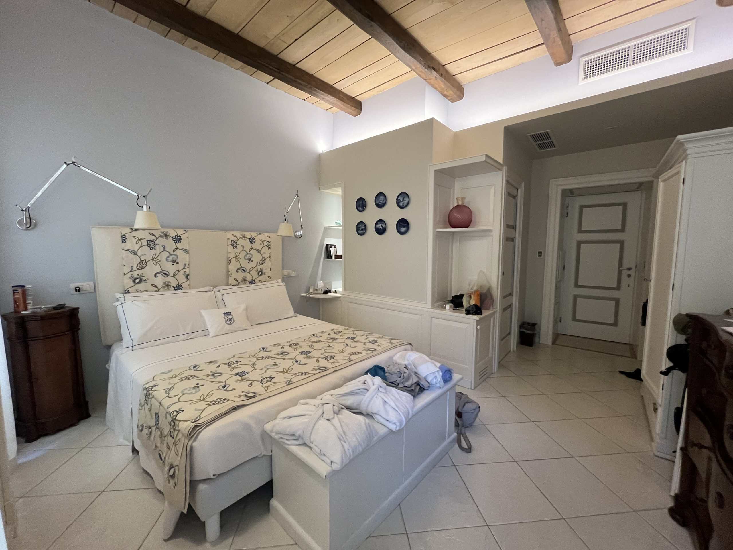 A hotel room with a bed lamps shelves in a nautical theme