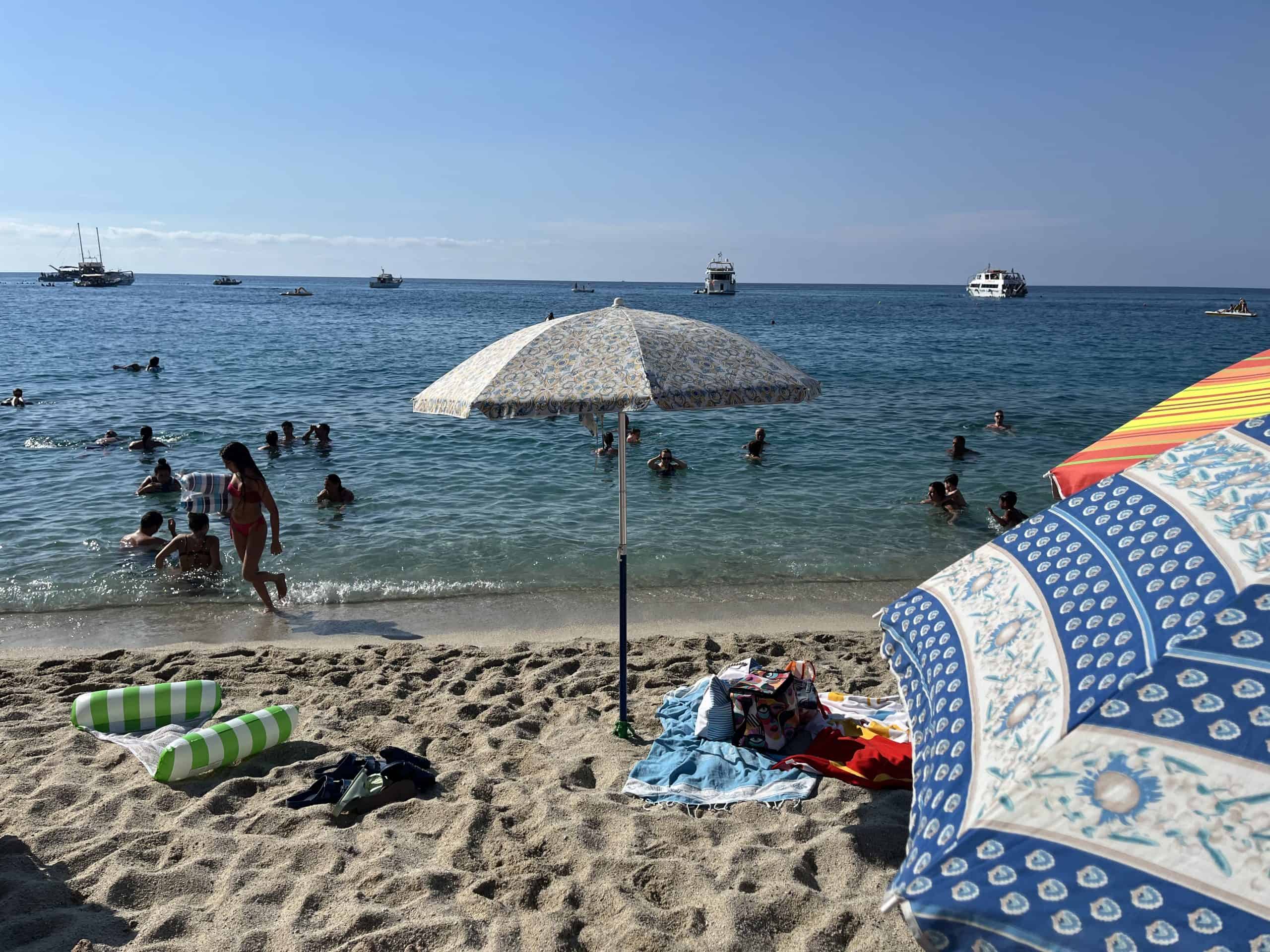 Beach umbrella with people swimming in the water behind it