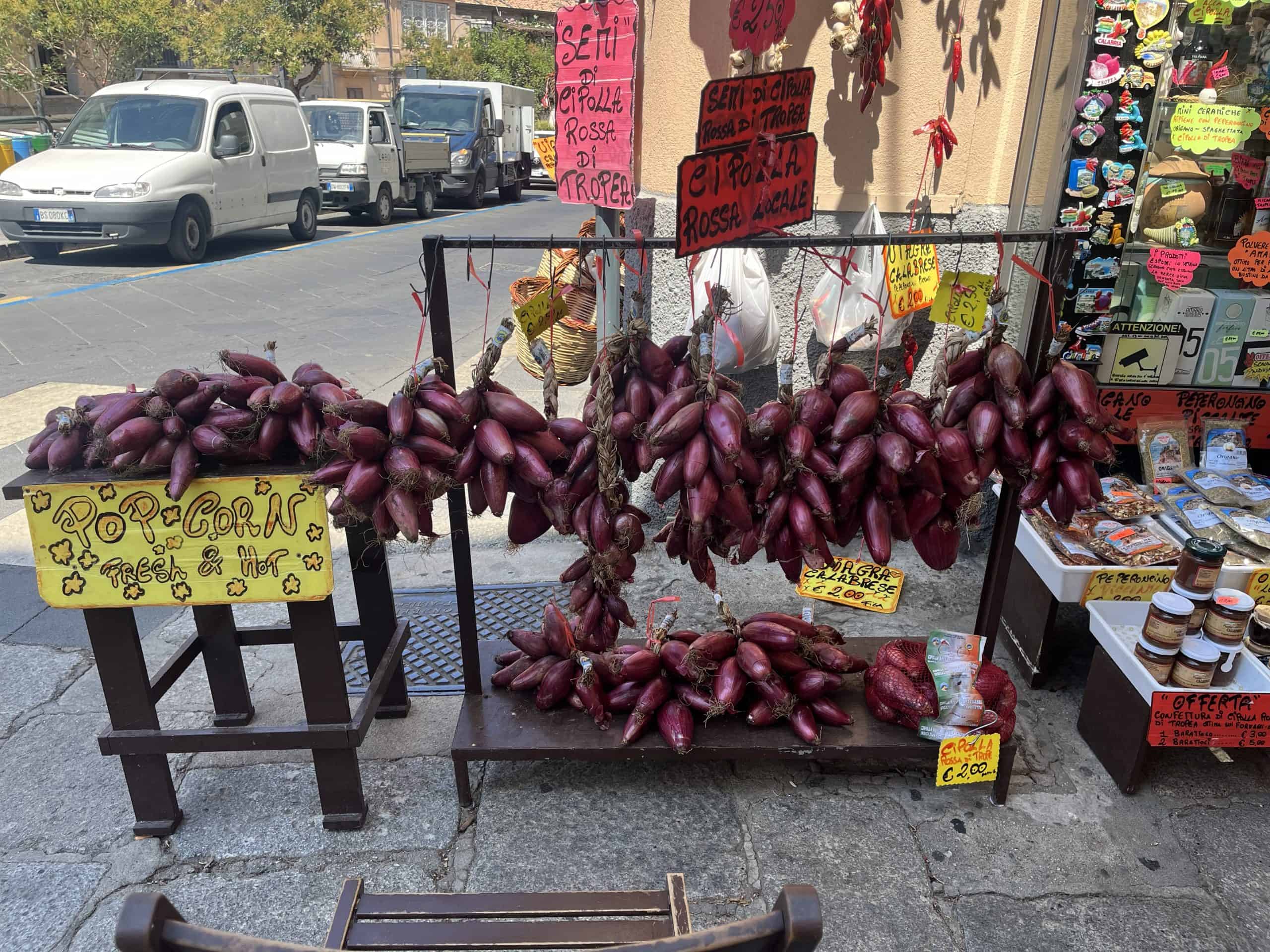 bunches of red onions for sale at a market stand in Tropea