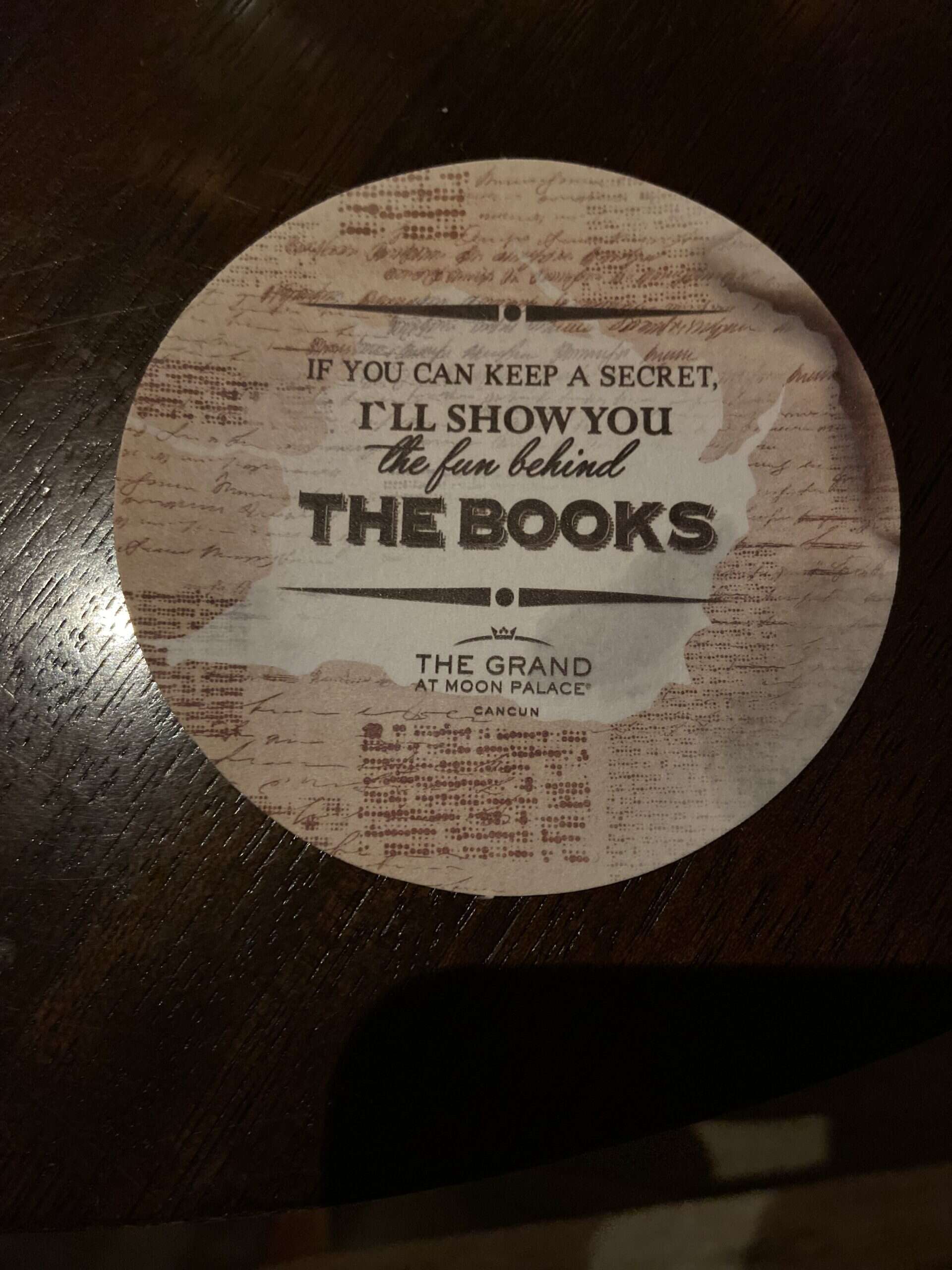 A round pieces of paper with the word The Books The Grand At Moon Palace Cancun
