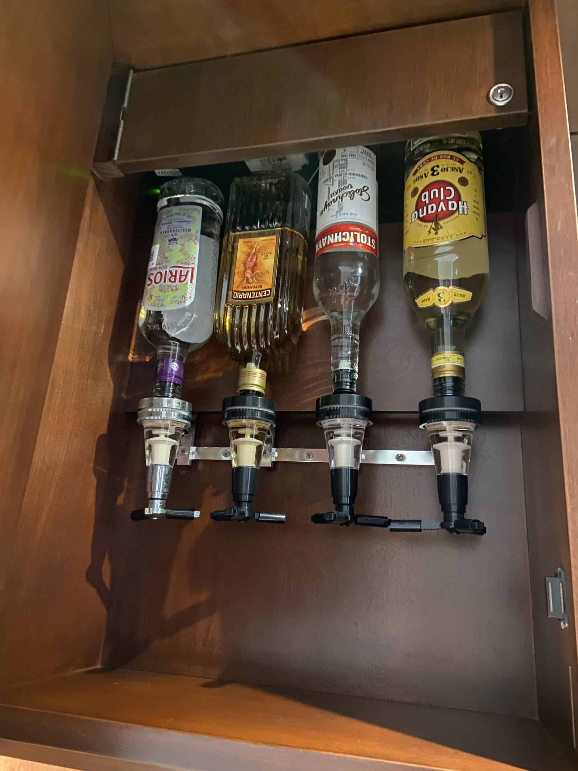 4 bottles of alcohol turned upside down in a cabinet to dispense