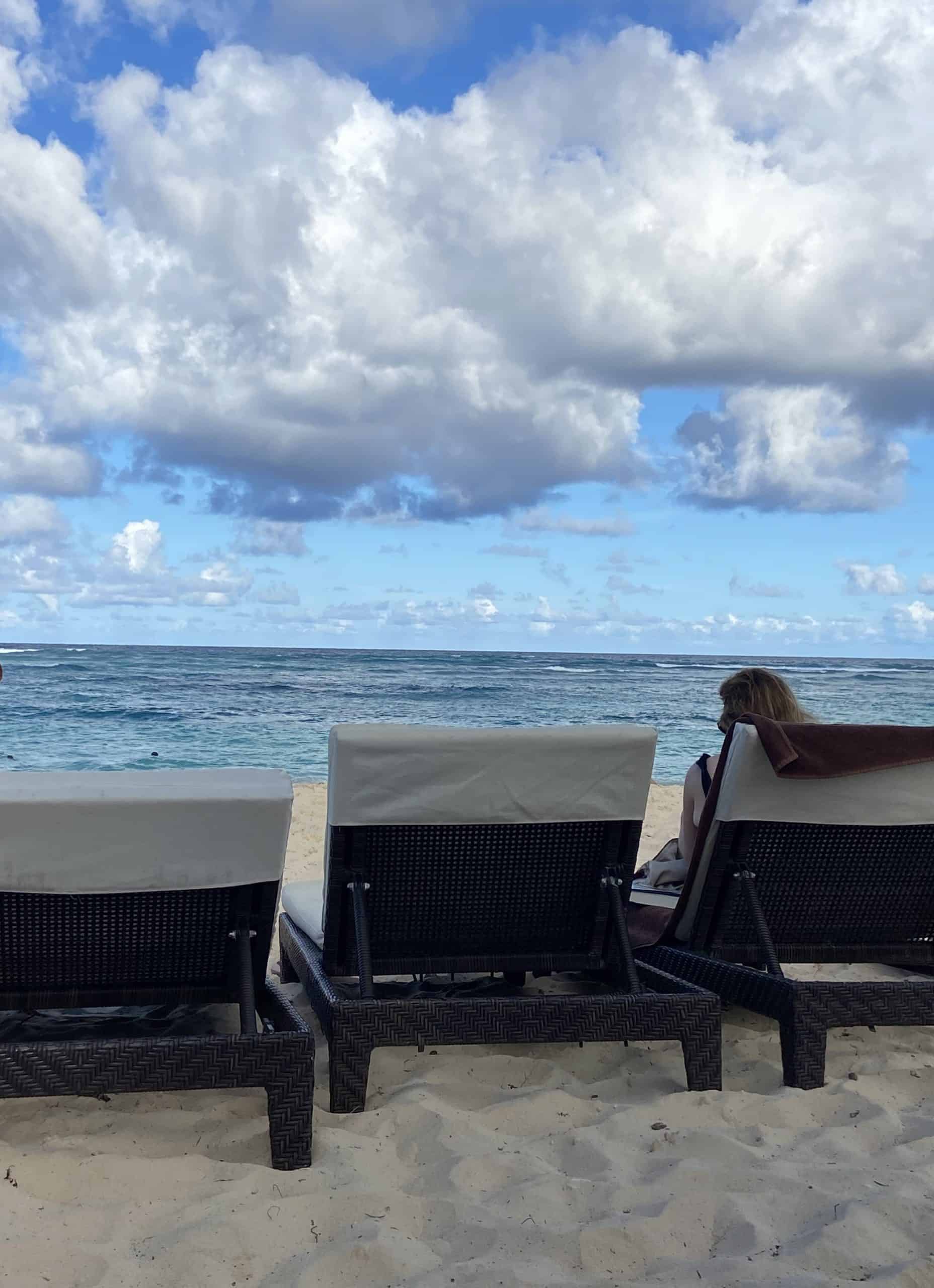 Clouds blue sky and back of beach chairs on sand