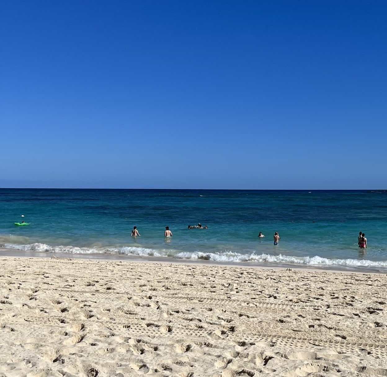 Blue sky above blue water and golden sand beach