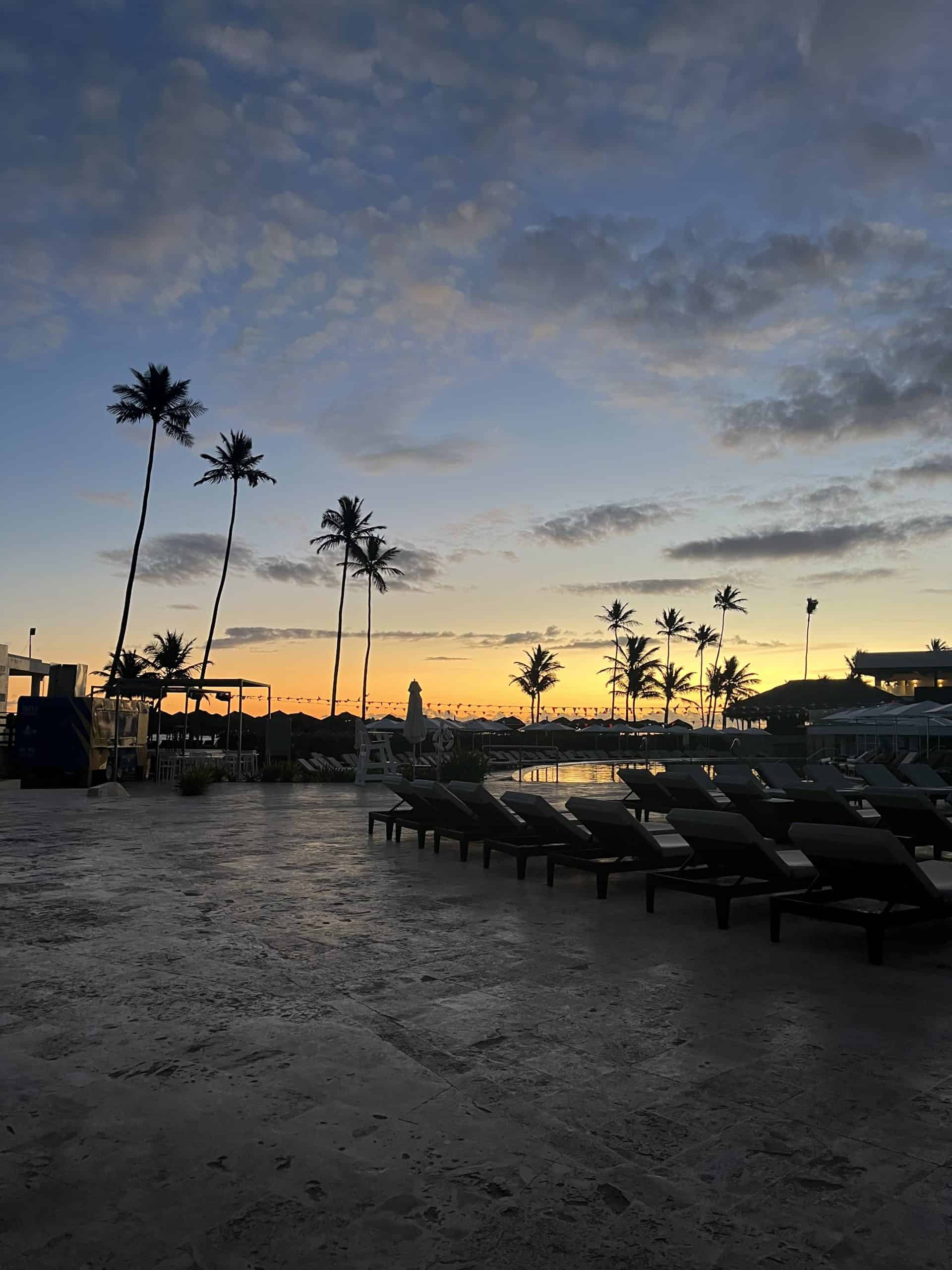 orange sunset with palm trees and pool chairs