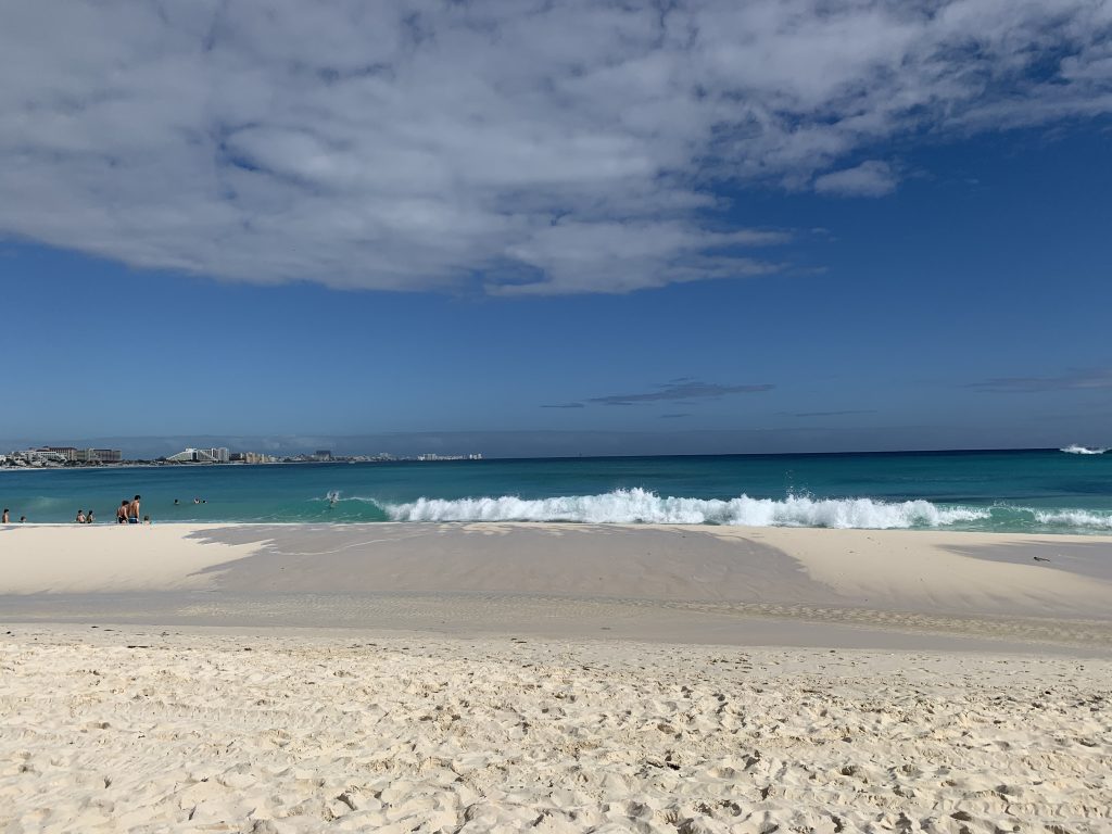 beach with blue water waves and clouds in the sky