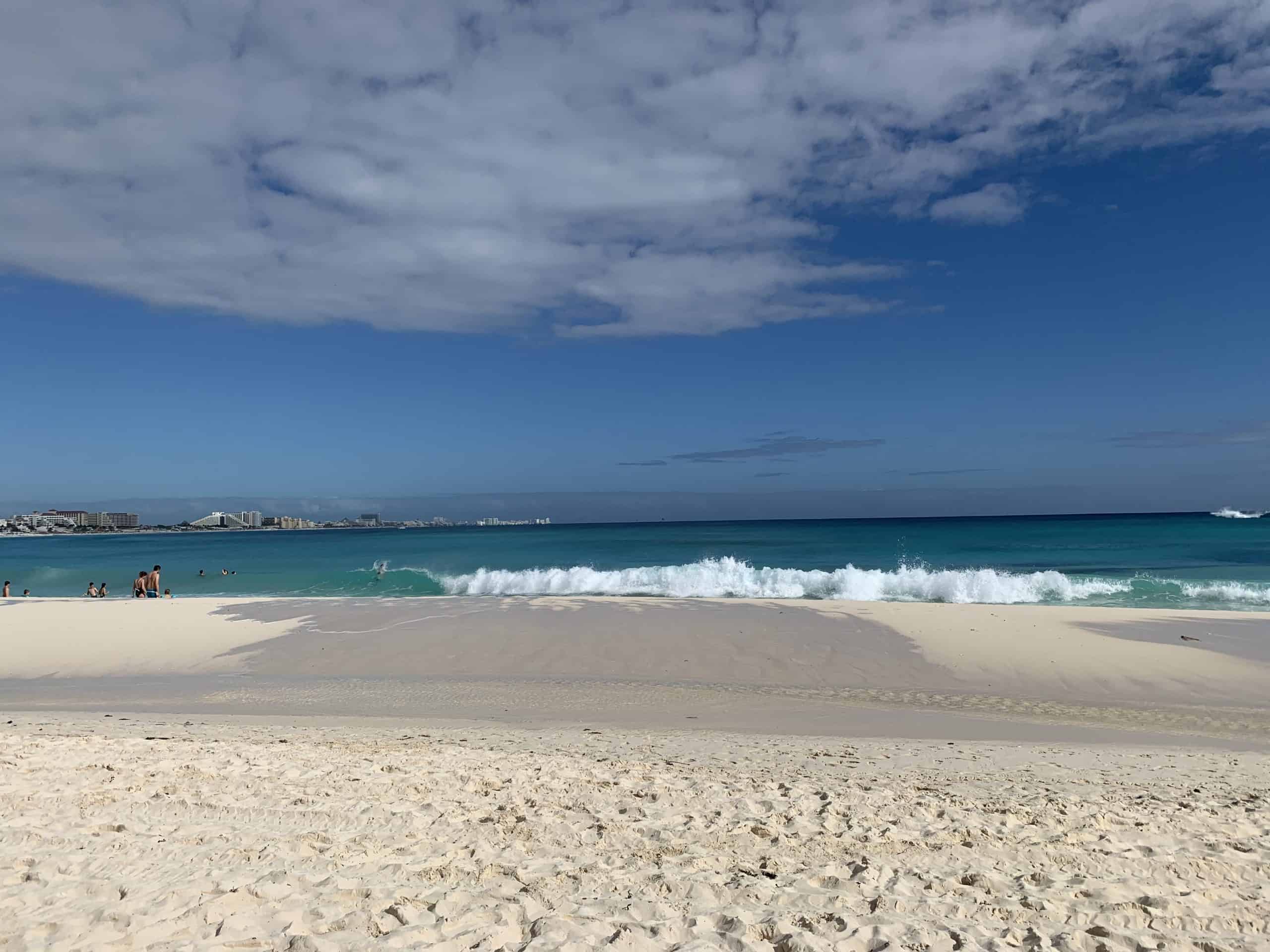beach with blue water waves and clouds in the sky