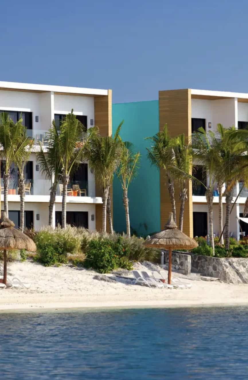 Oceanfront hotel room buildings with palapas and chairs