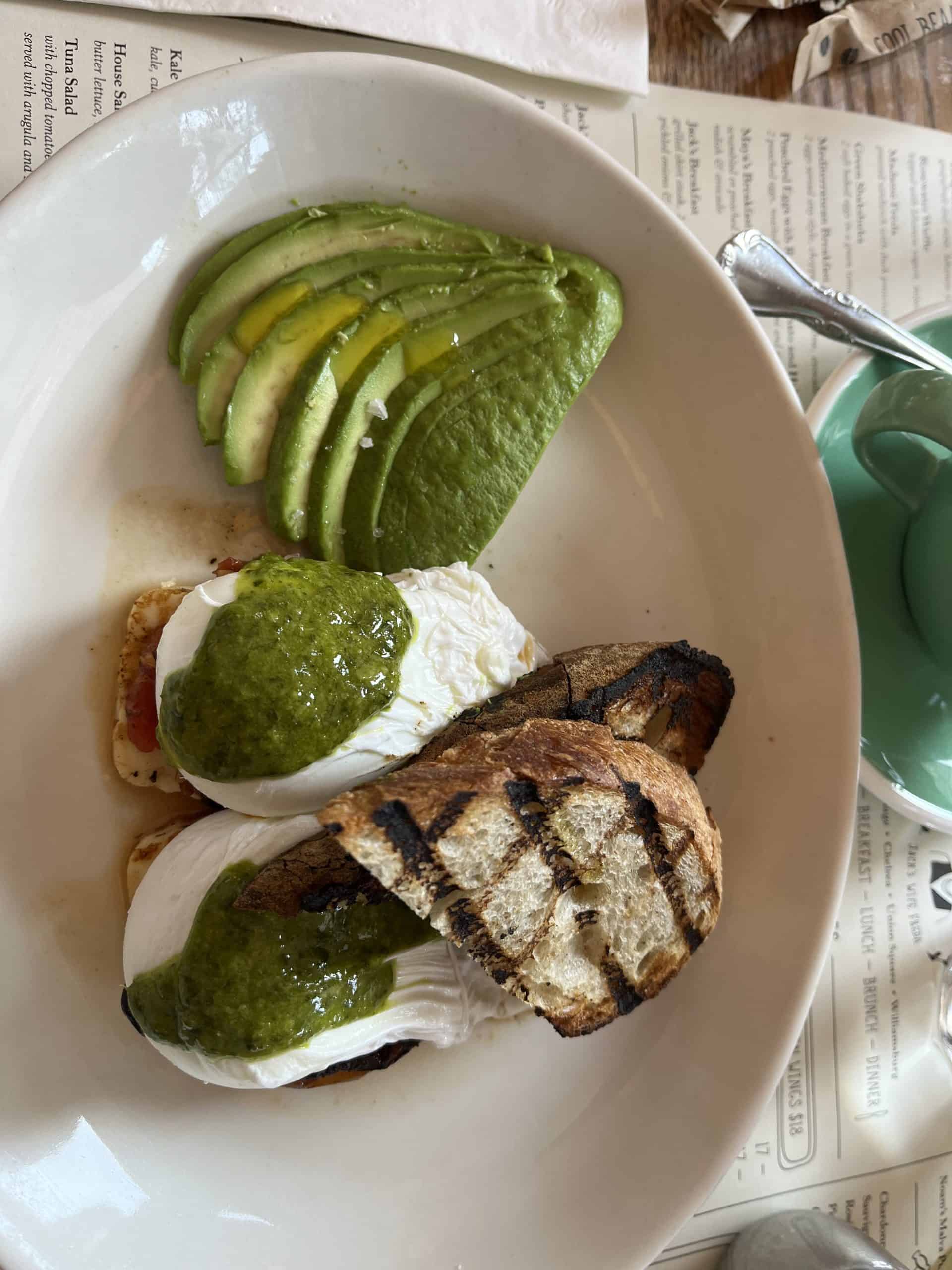 Avocado slices next to eggs benedict and pieces of toast