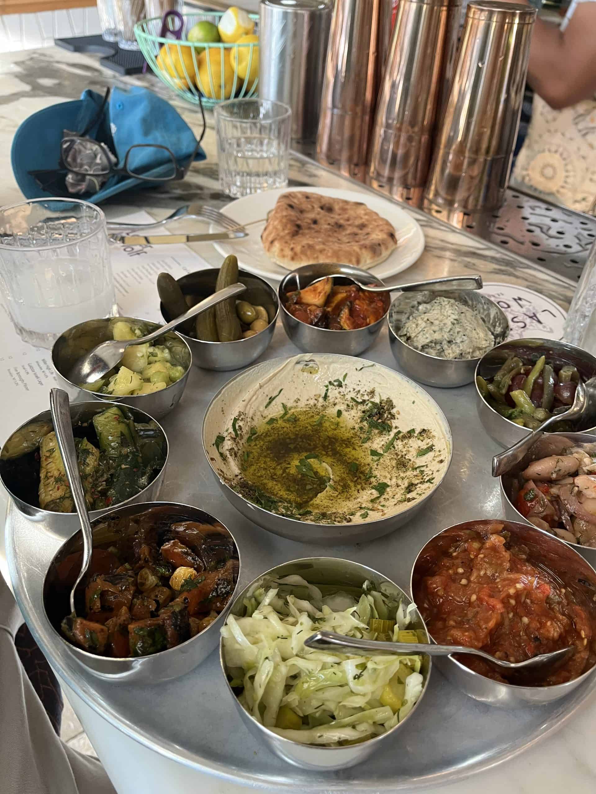 Round platter of bowls with Mediterranean dips and pita