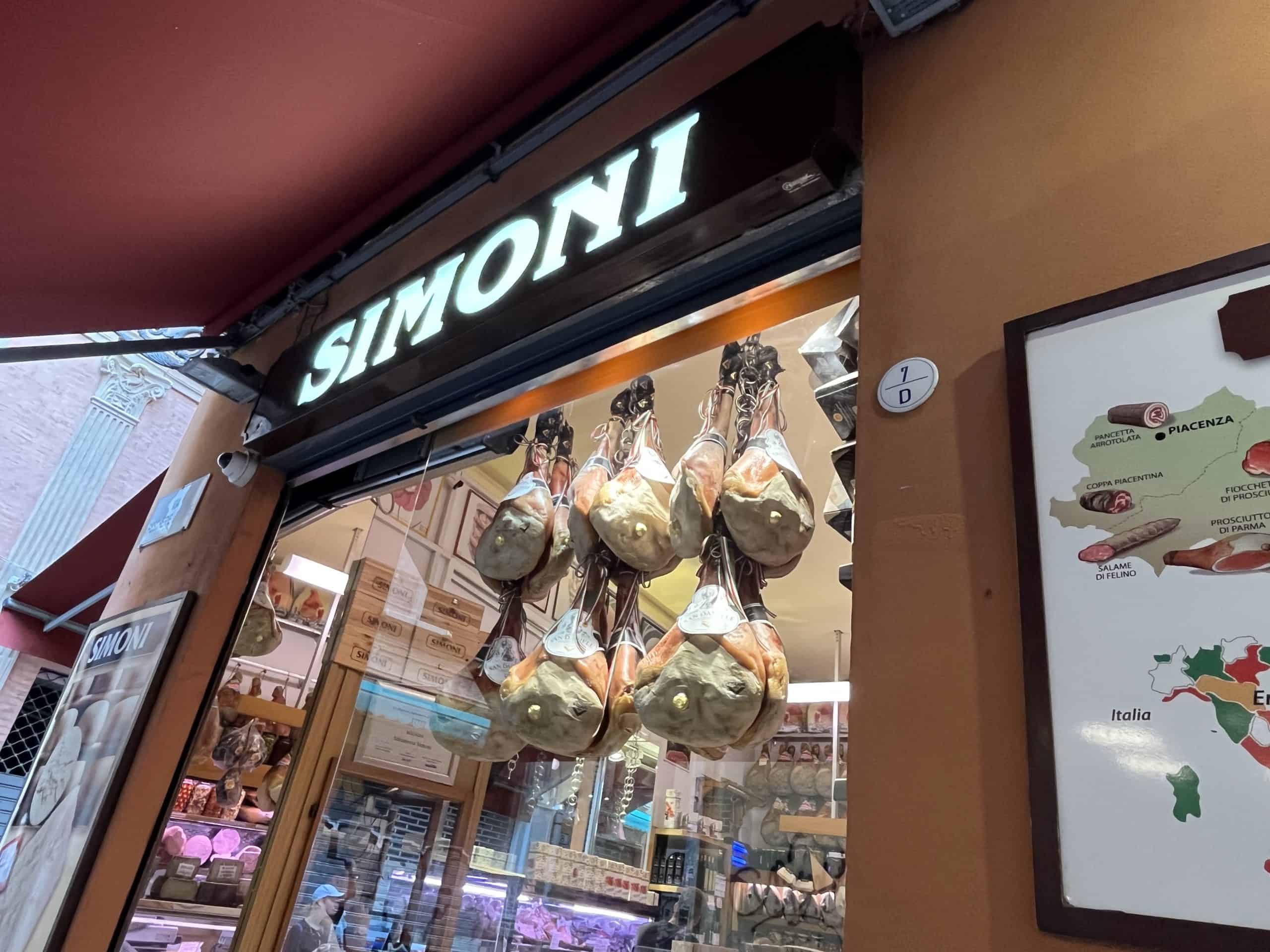 A storefront display featuring hanging cured meats and Italian food products