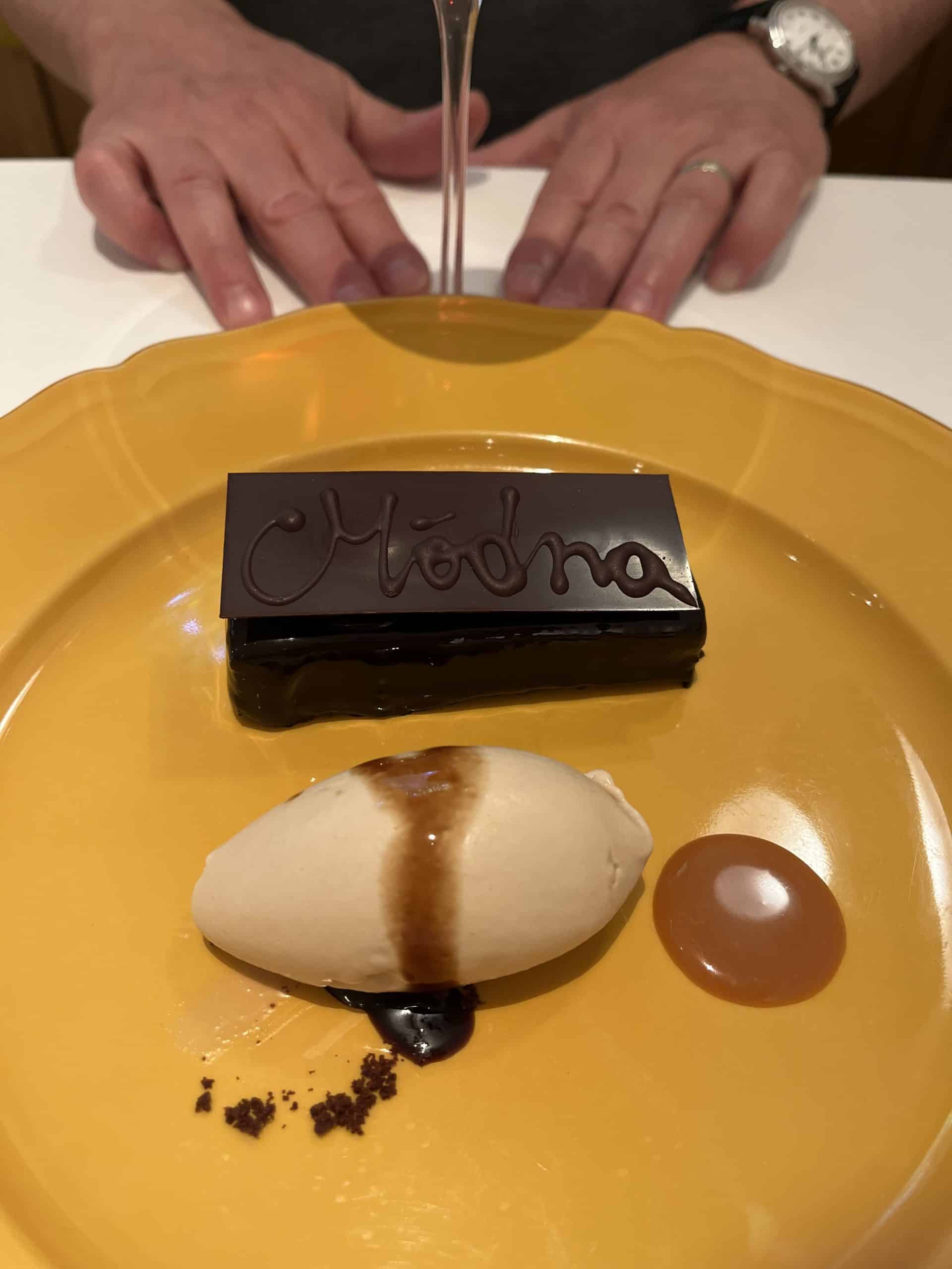 Decadent chocolate dessert with personalized “Modena” chocolate plaque, served with cream and caramel sauce.