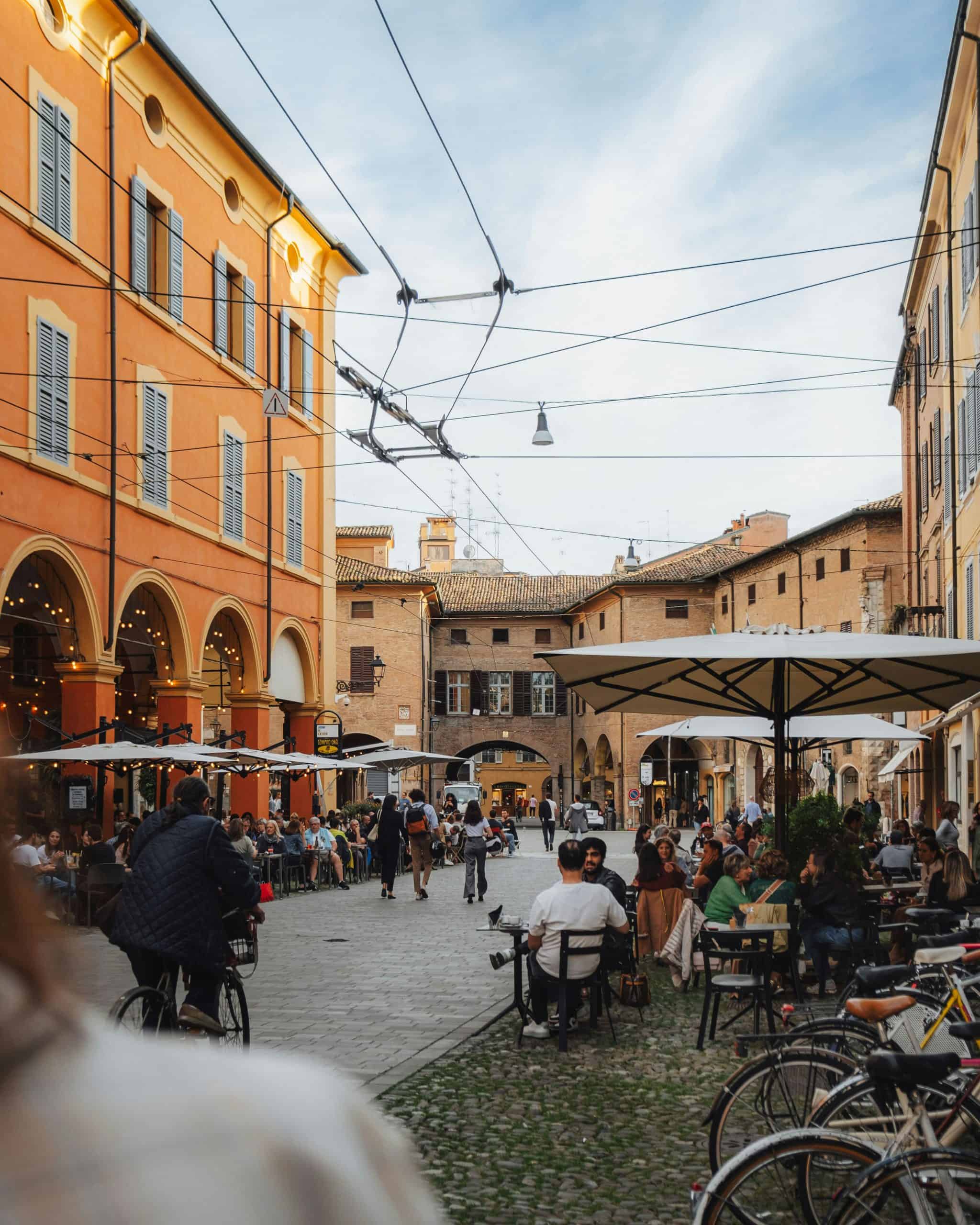 people sitting at tables and chairs in a town square