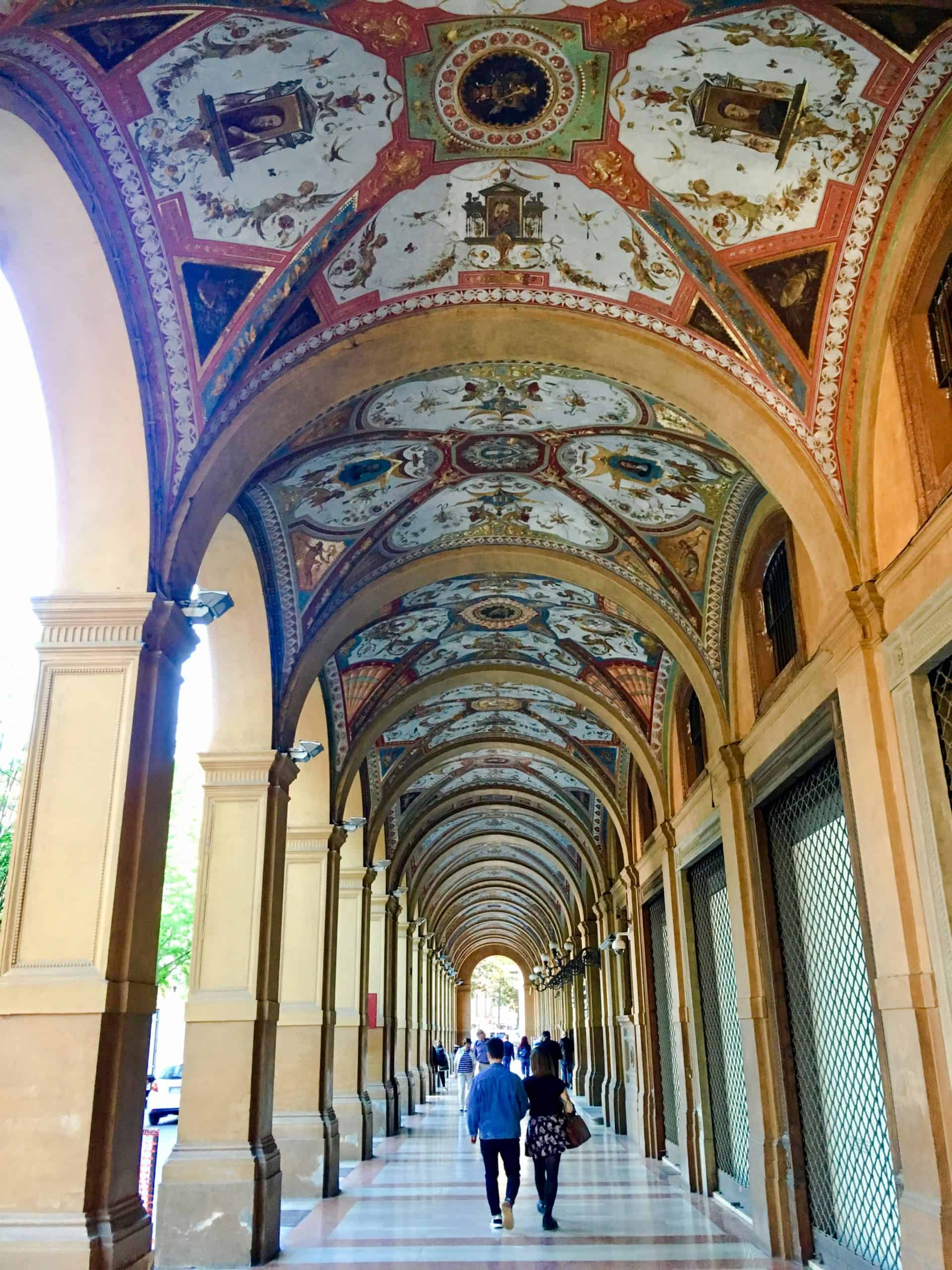 People walking under porticos in Bologna