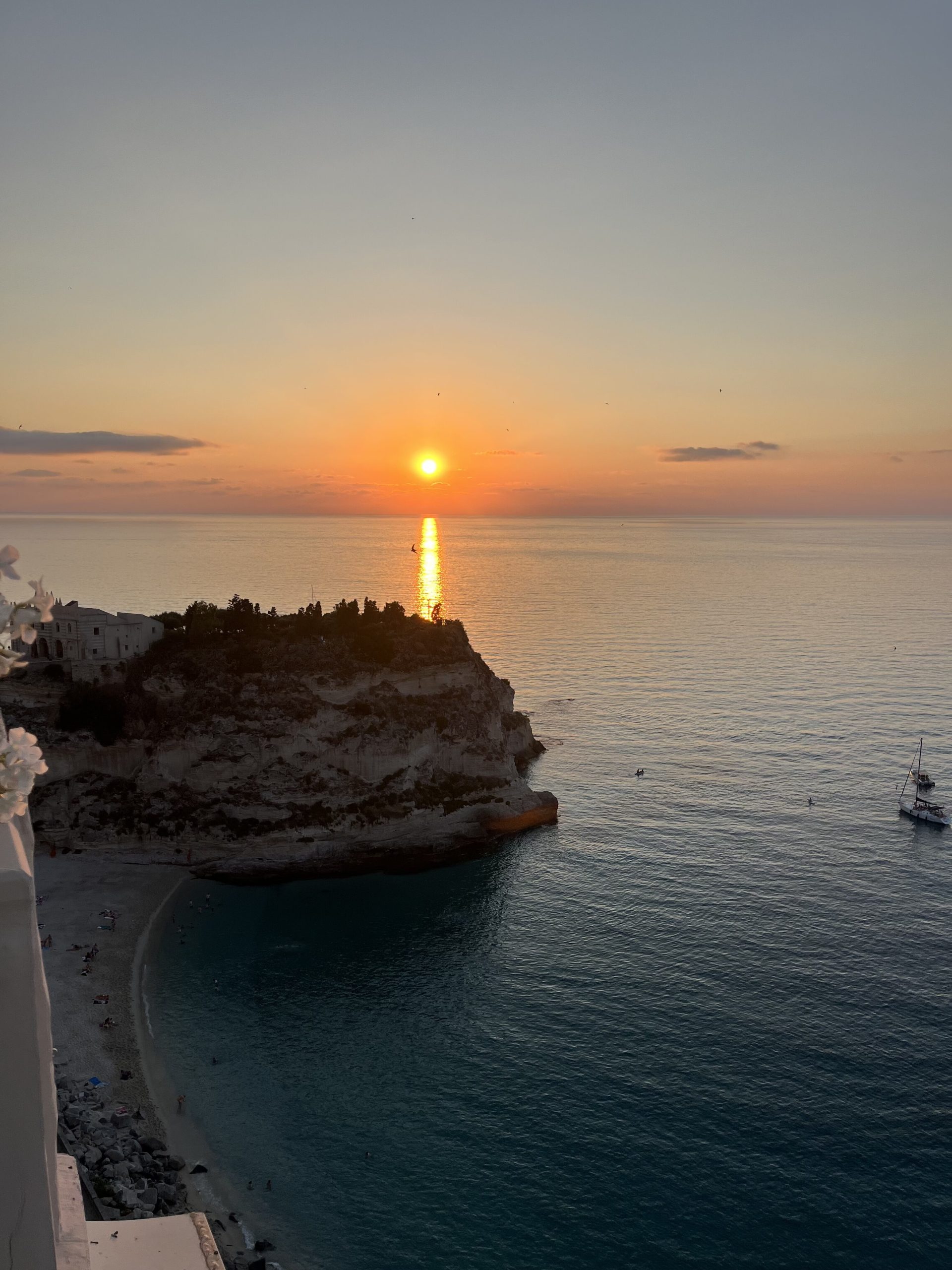 Orange sun setting in background over the sea in Tropea