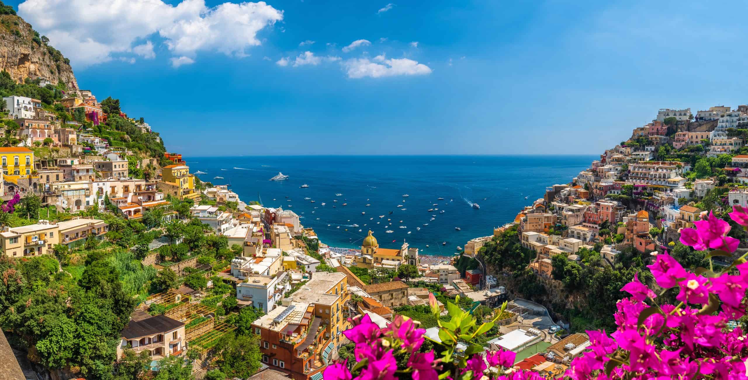 Sea view with cliffside buildings surrounding and pink flowers