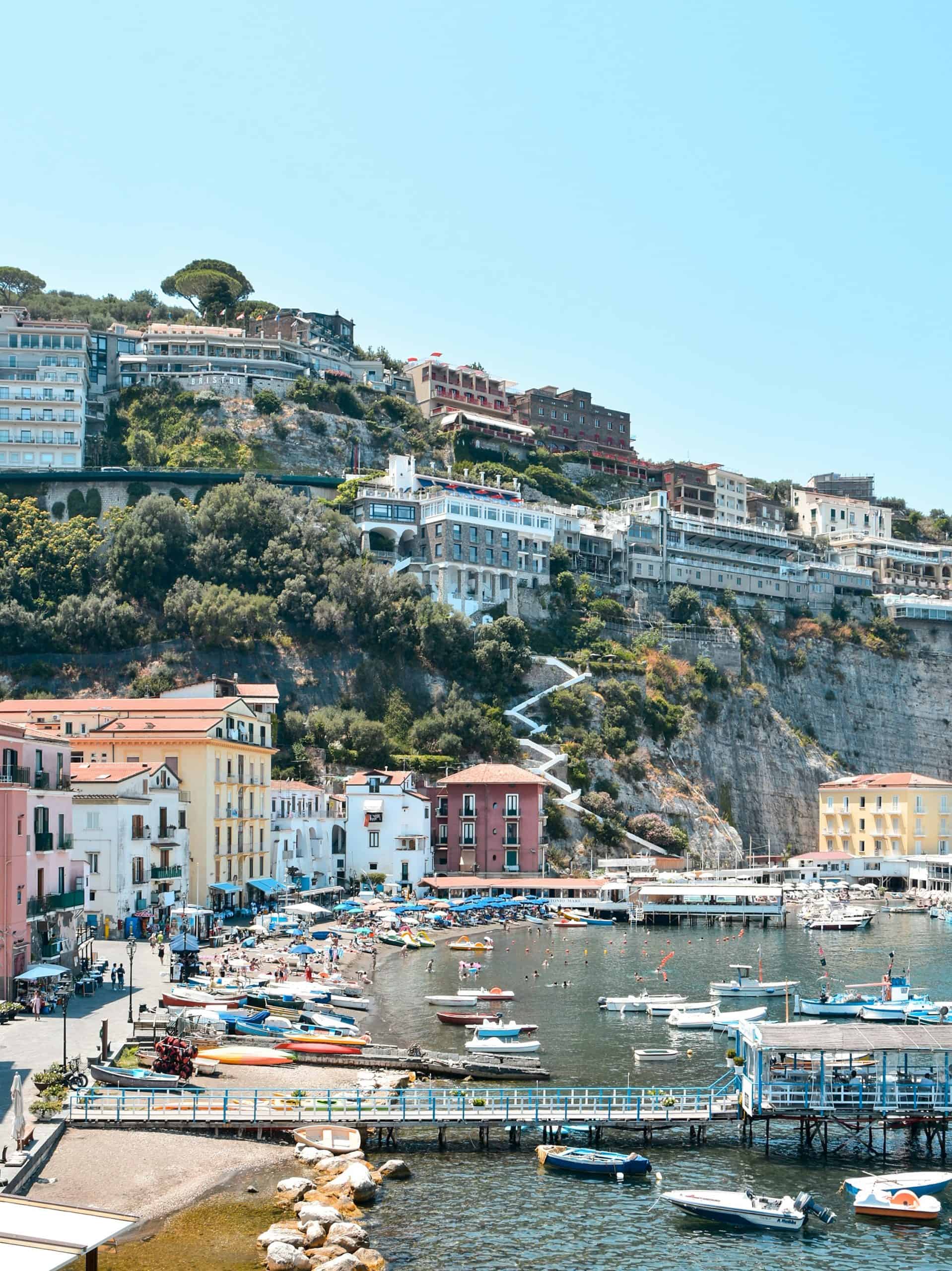 boats at a seaside port with buildings high up on a cliff