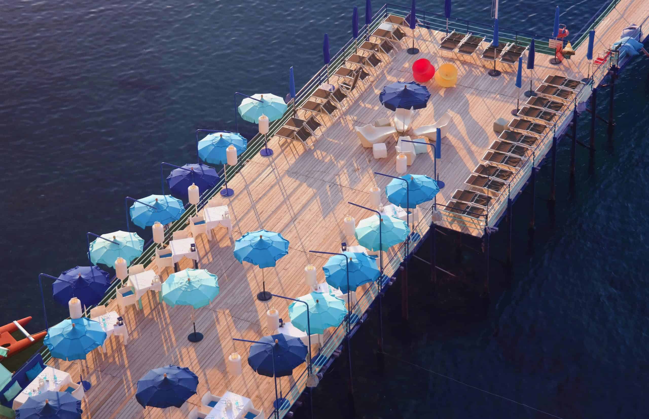 sunbeds and open umbrellas on a platform above the sea