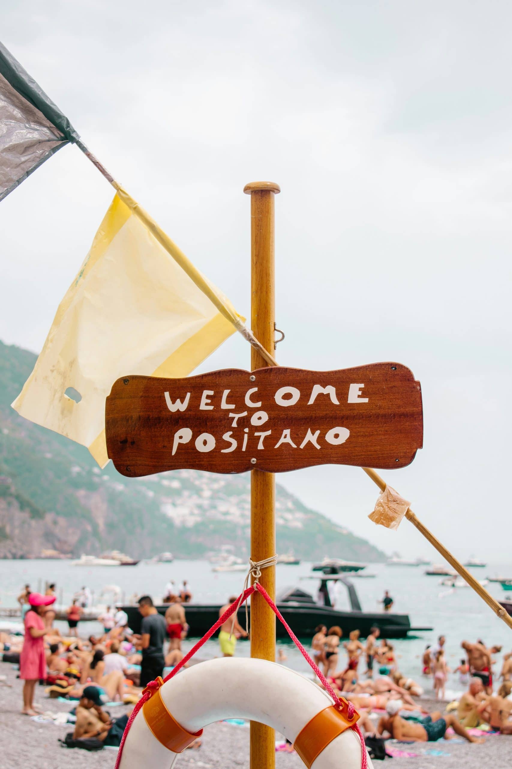 Beautiful Positano seaside with travelers relaxing, boats, and scenic mountain backdrop.
