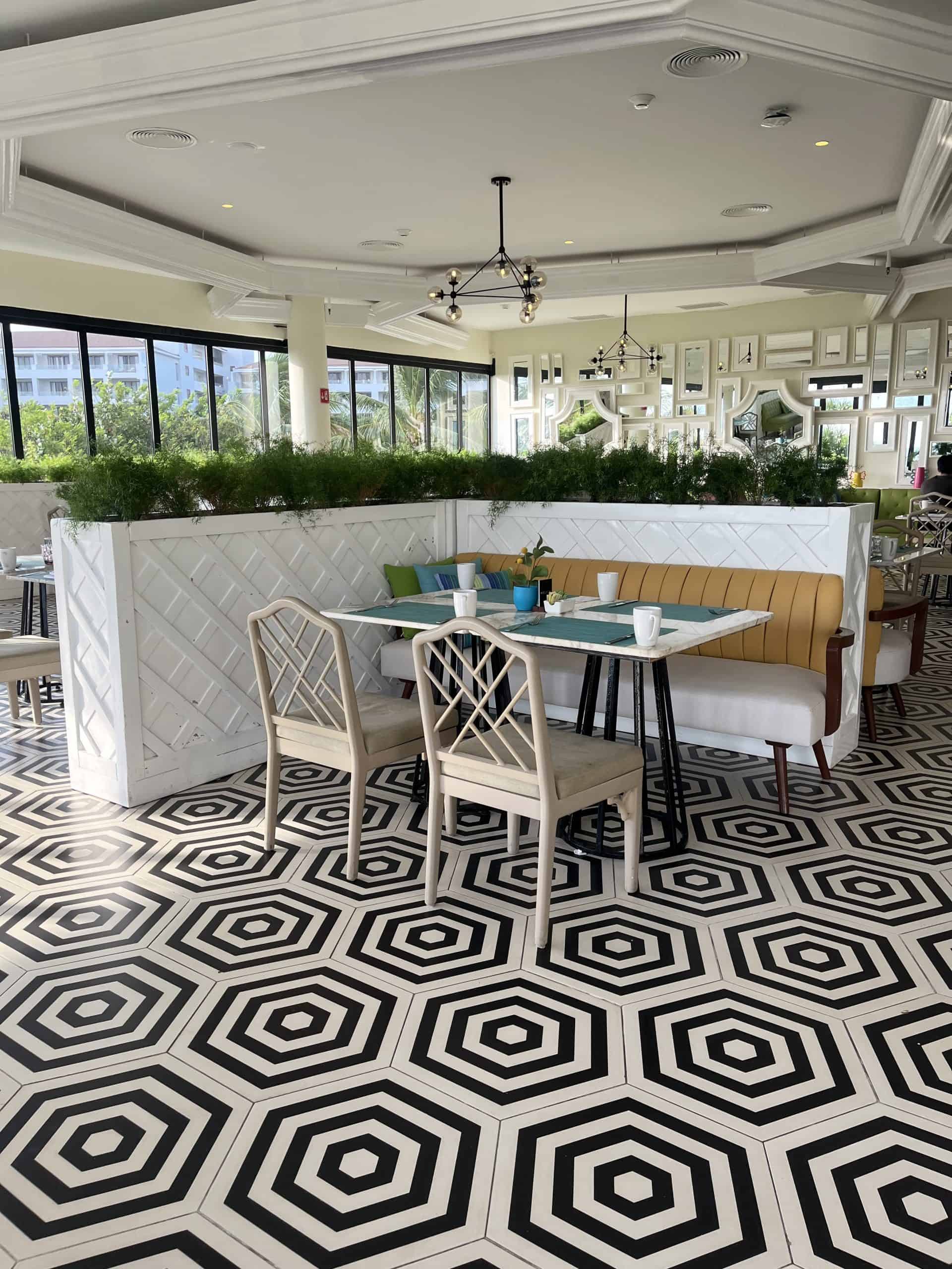 Inside of a restuarant with black and white designs on the floor and yellow seating booths