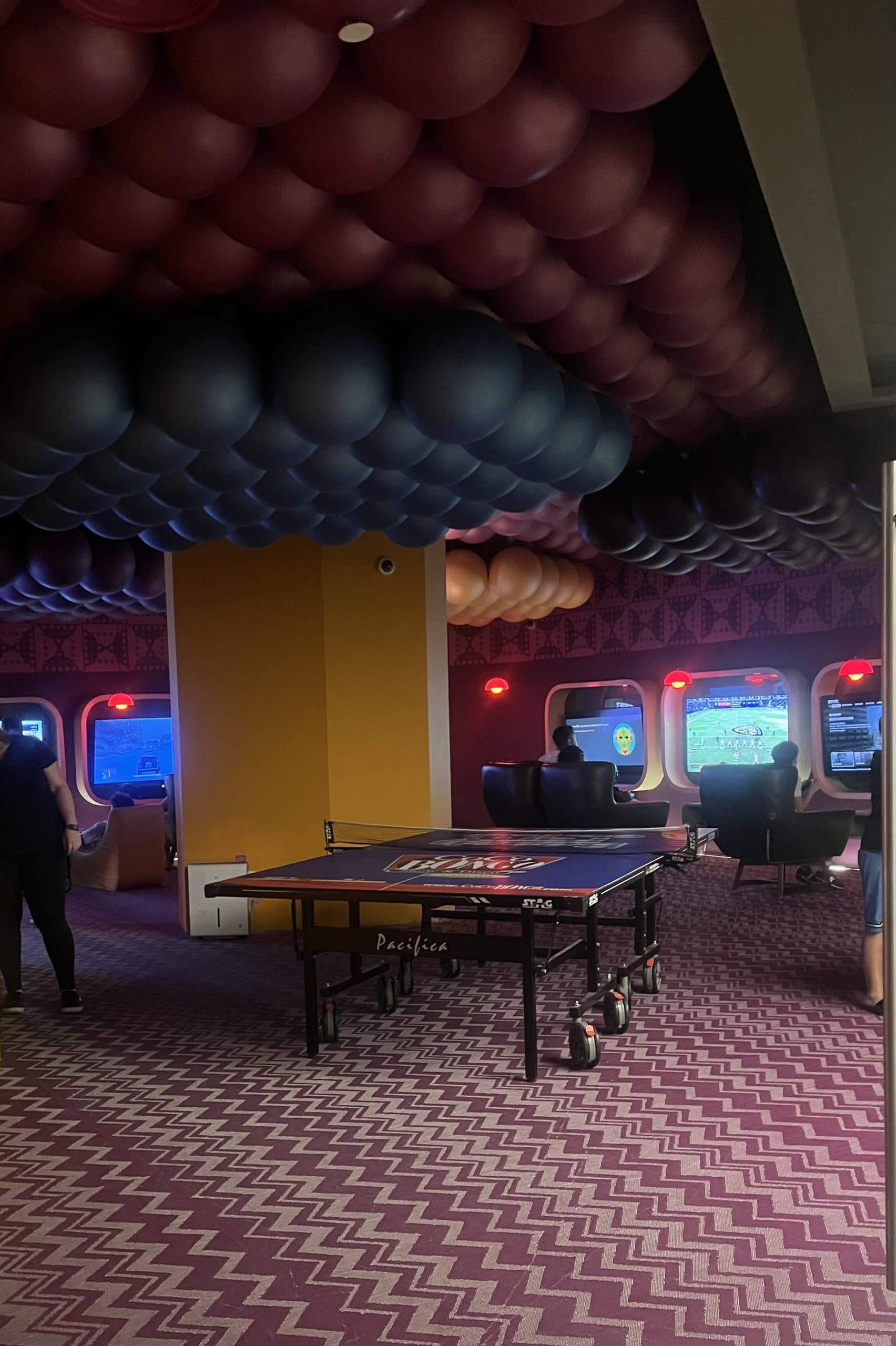 Purple lounge with video game stations and a ping pong table