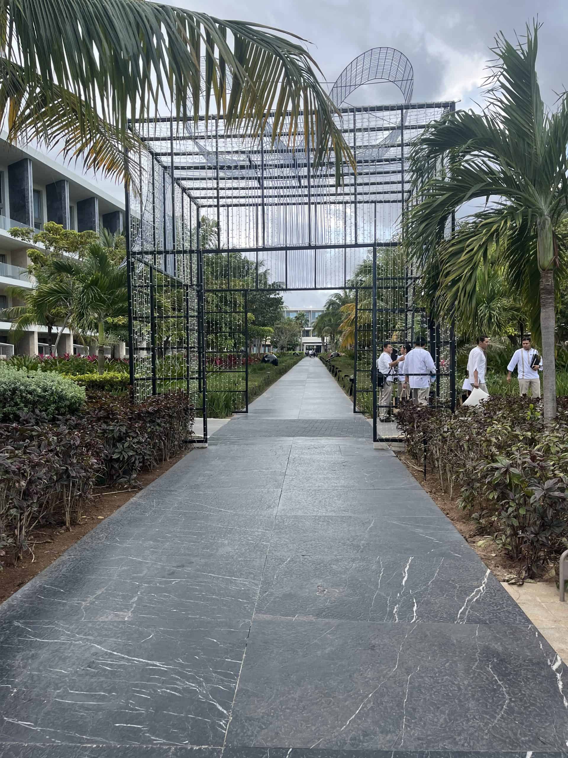 walkway at a hotel resort with palm trees and building in background