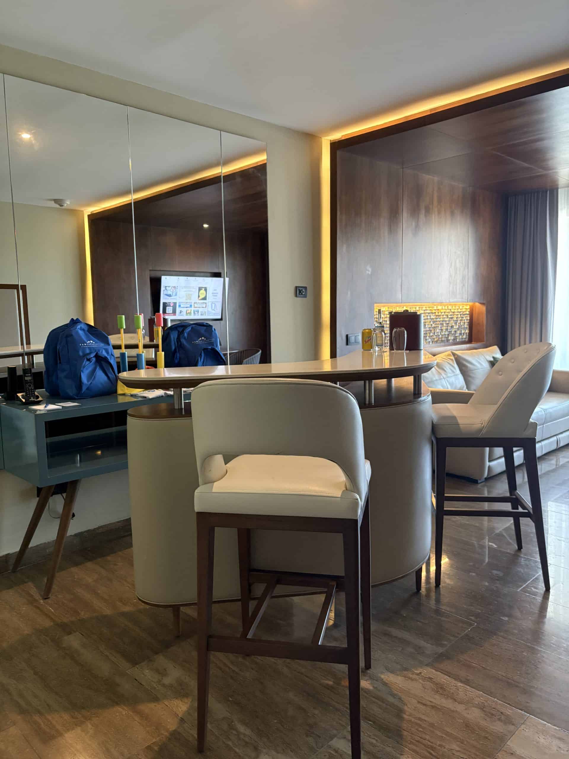 Oval island table and stools in a room with a mirror and brown wall
