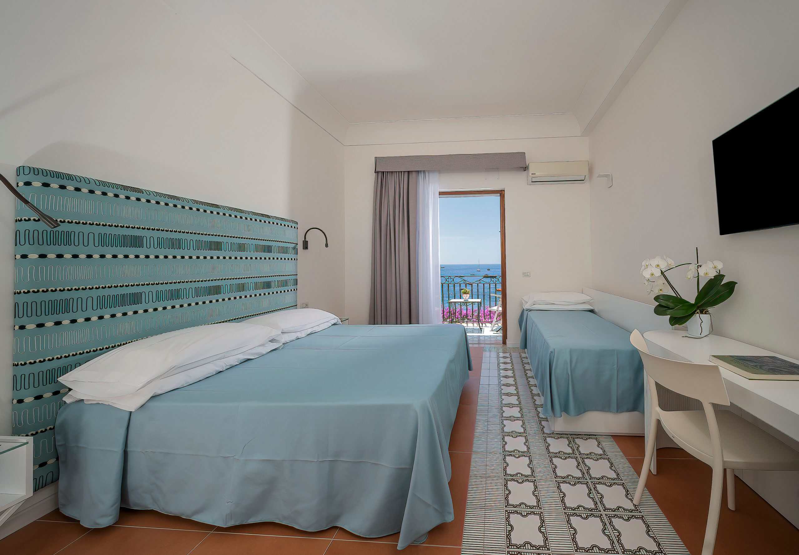 Hotel room with the blue sea view out of the terrace door