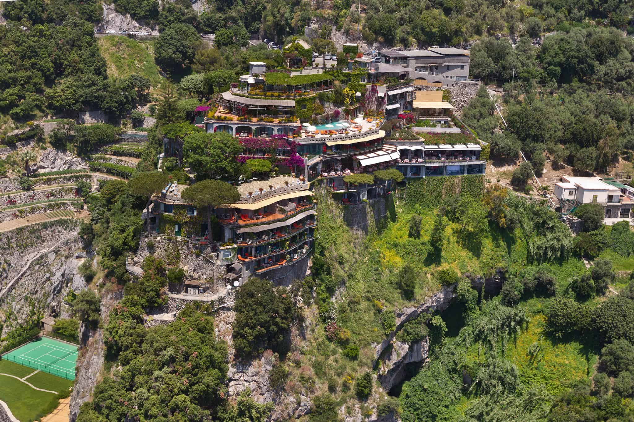 Cliffside luxury hotel with stunning views and lush gardens in a hillside setting.
