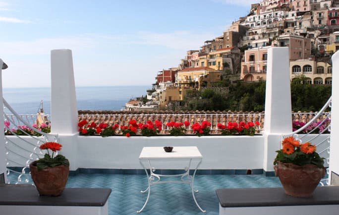 Beautiful balcony overlooking Amalfi Coast with colorful hillside houses and ocean view.