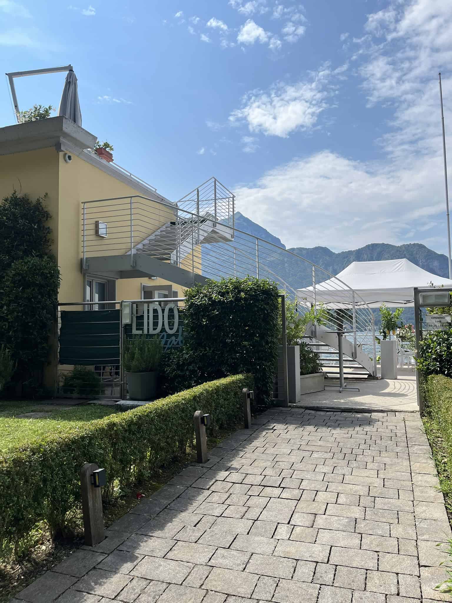 Outdoor winding staircase to restaurant on lake with mountain behind it