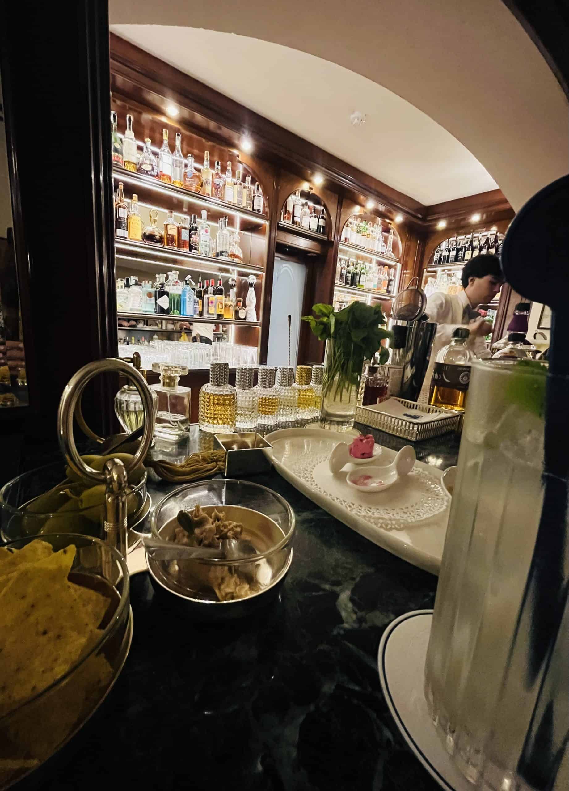 bartender with bottles behind him as he makes a drink