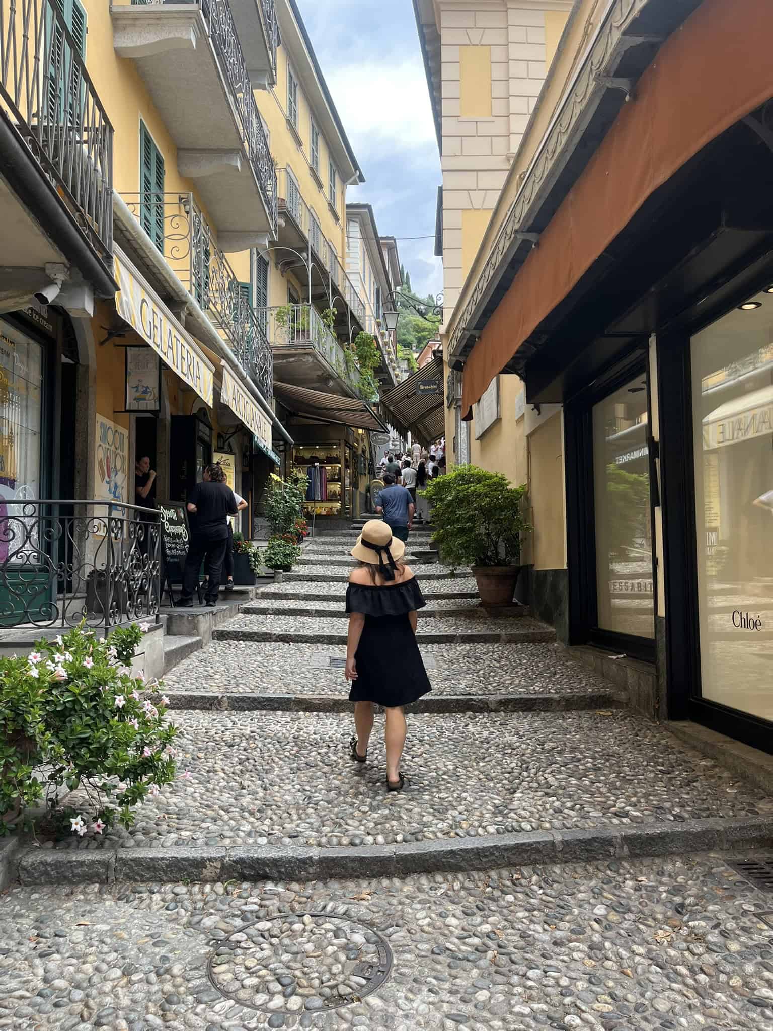 Woman with a hat walking up a cobblestone walkway