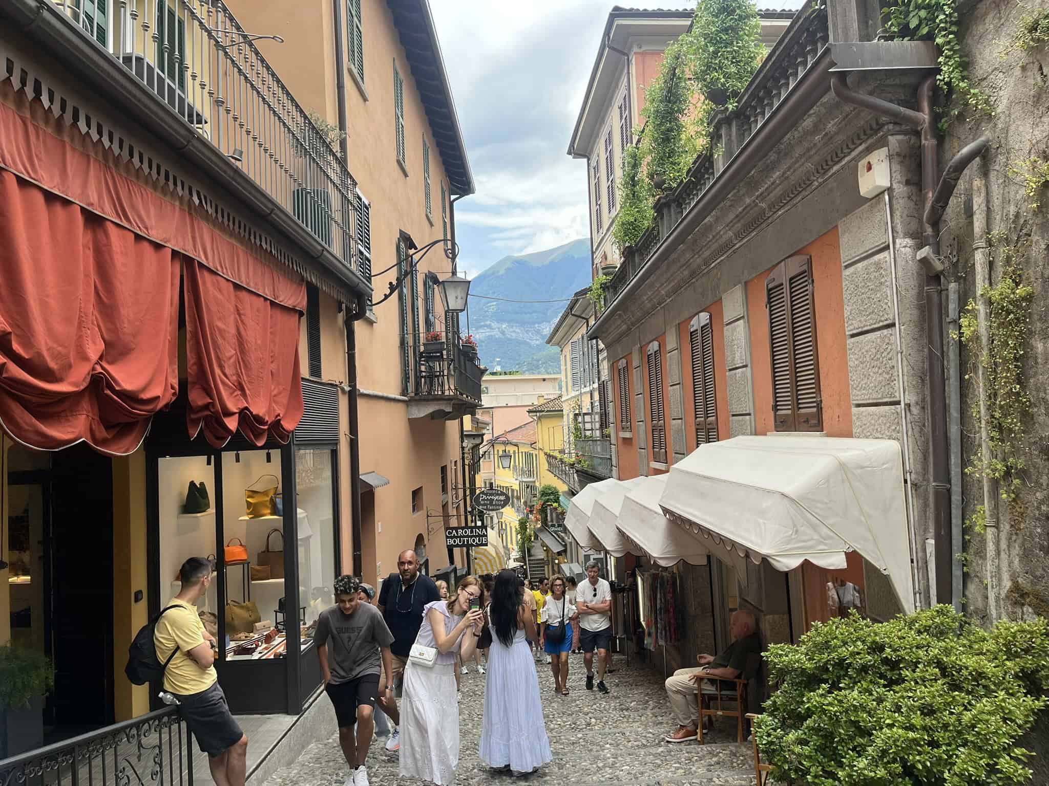People walking along cobblestone walkway with stores on either side