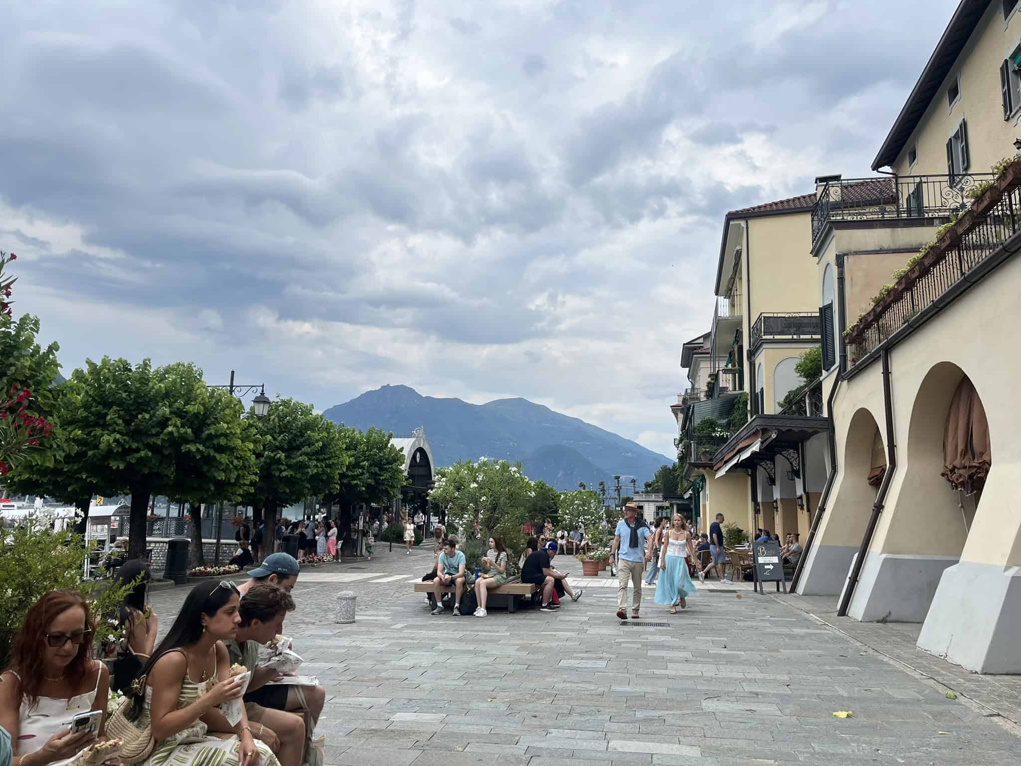 People walking on the lakefront promenade with mountains in the background